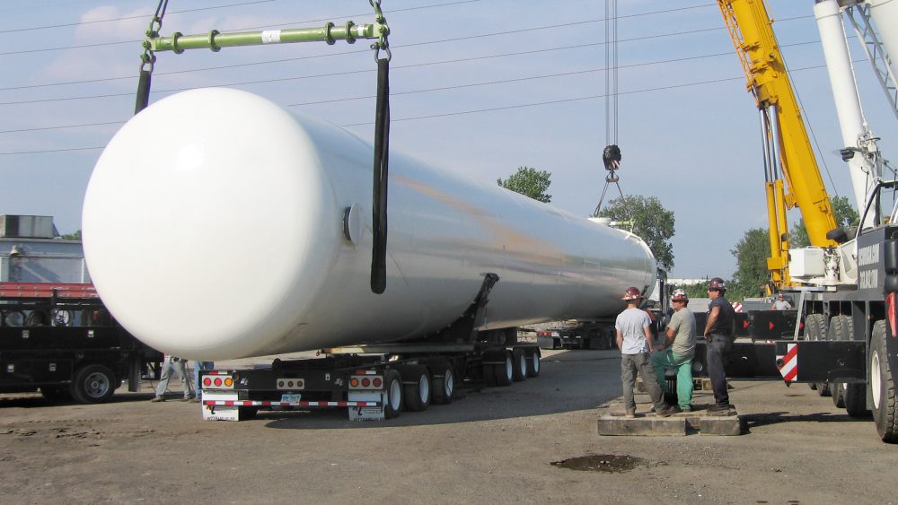 A surge drum being offloaded from a steerable dolly trailer.