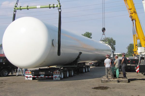 A surge drum being offloaded from a steerable dolly trailer.