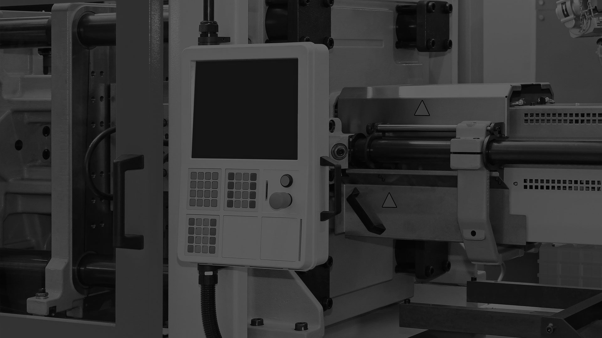 A darkened black and white image of an injection molding machine.