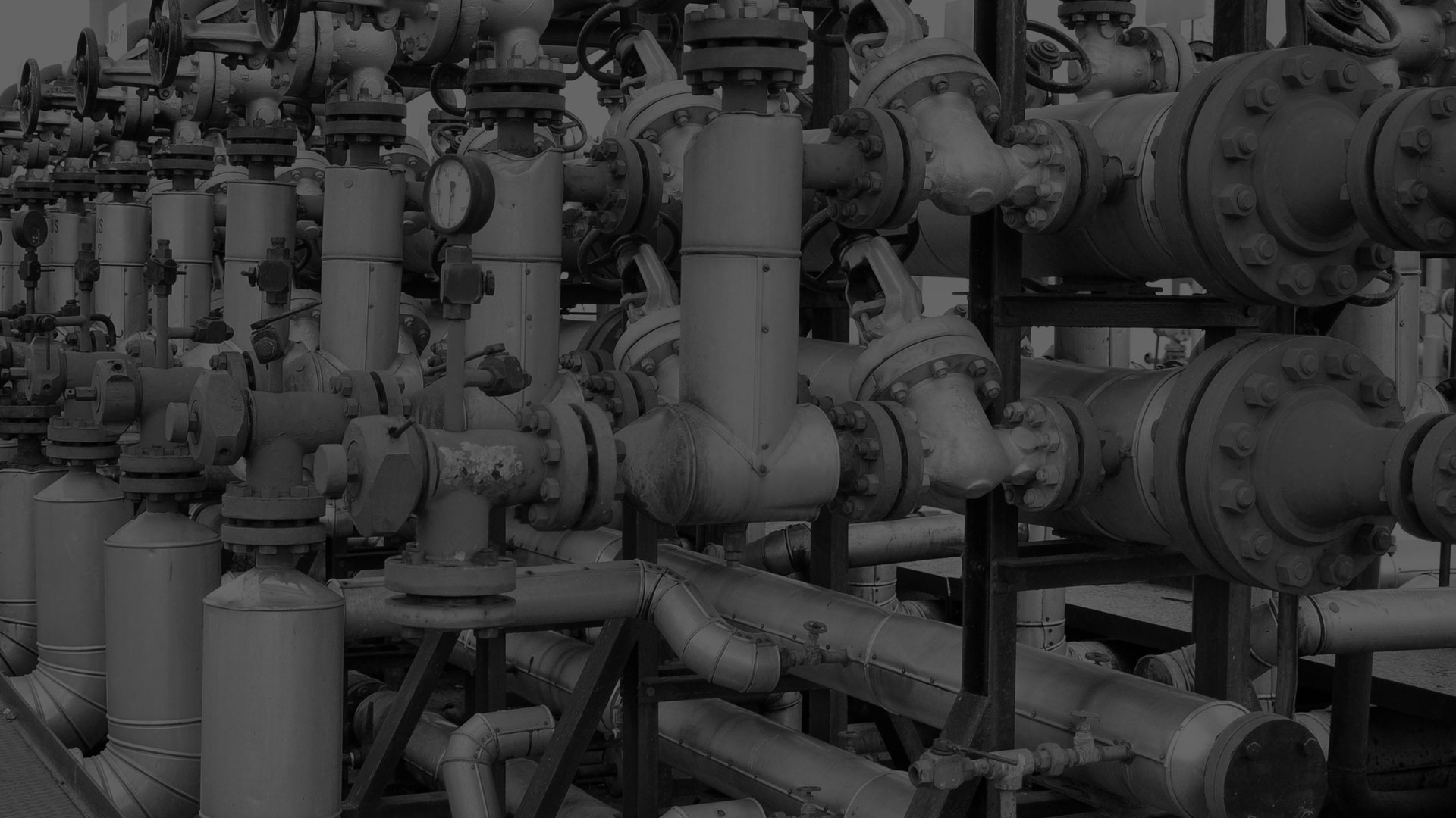 A darkened black and white image of an oil and gas pipe rig.