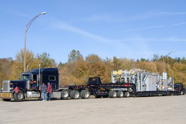 A loaded perimeter 13 axle trailer sitting in a rest area loaded with an oil and gas rig.