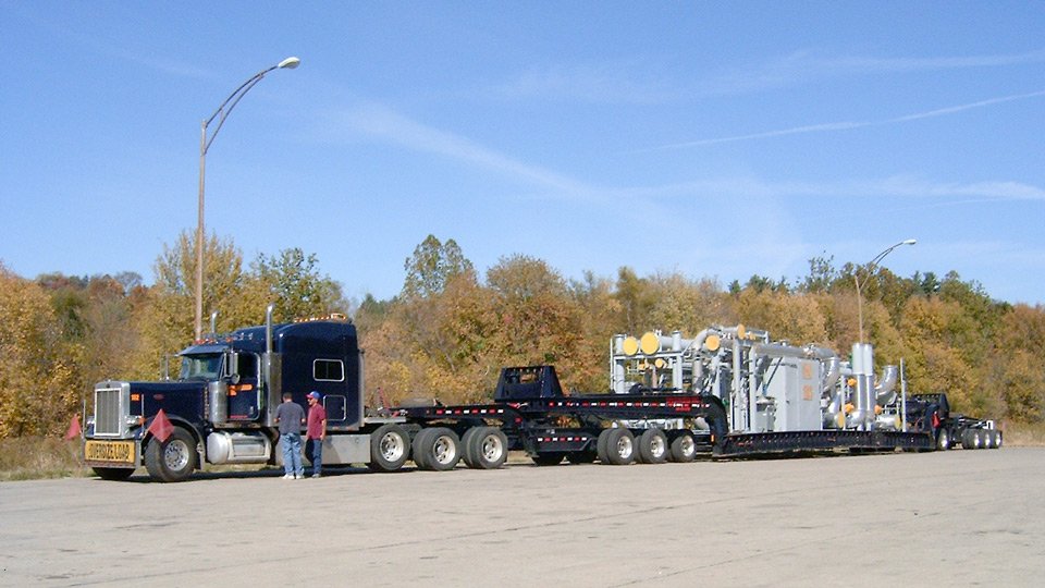 A loaded perimeter 13 axle trailer sitting in a rest area loaded with an oil and gas rig.
