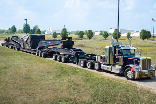 A 20 axle rig loaded with a Press Crown outside a customers facility.