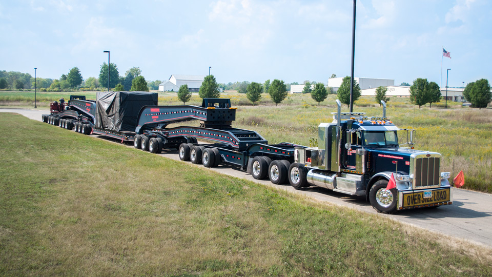 A 20 axle rig loaded with a Press Crown outside a customers facility.