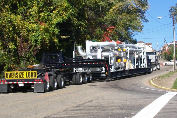 A superload makes its way up a hill on narrow city streets.