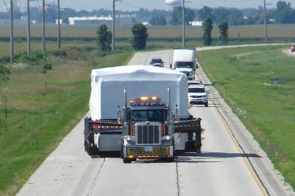 A front view of a oversize load taking up both lanes of the highway.