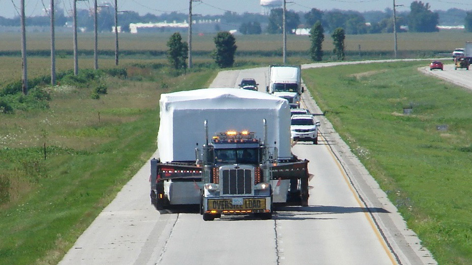 A front view of a oversize load taking up both lanes of the highway.