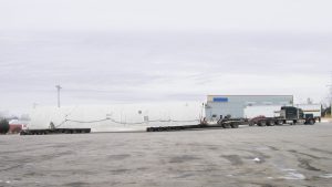 A side view of a steerable dolly setup loaded with a cold box sitting in a truck stop