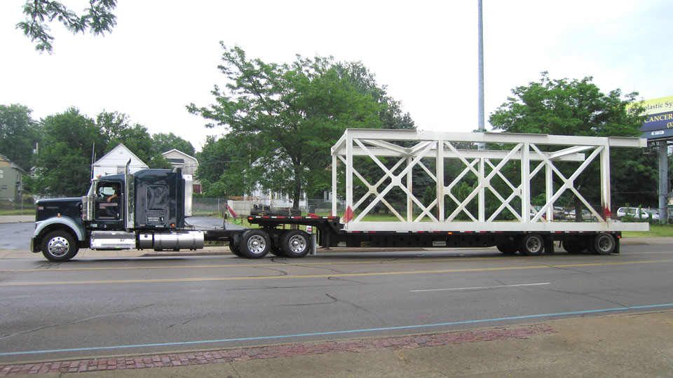 A standard stepdeck hauling a oversize load bridge section.