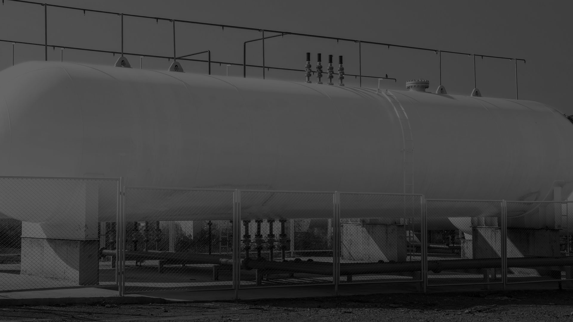 A darkened black and white image of a horizontal tank.