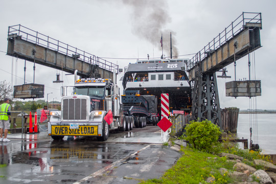 A 20 axle trailer being backed into the underbelly of a ferry.
