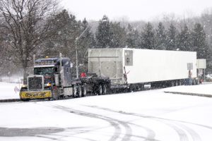 A oversive load makes its way into a rest area through harsh winter conditions.