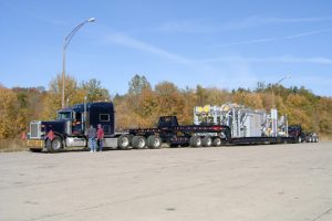 A loaded perimeter 13 axle trailer sitting in a rest area loaded with an oil and gas rig.